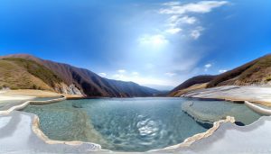 Une vue panoramique d'une piscine naturelle avec des sources chaudes dans un environnement montagneux.