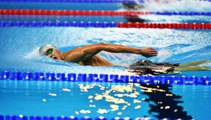 Un nageur professionnel en plein effort dans une piscine olympique.