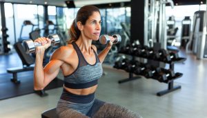 Une femme en train de faire des exercices de musculation pour les bras avec des haltères.